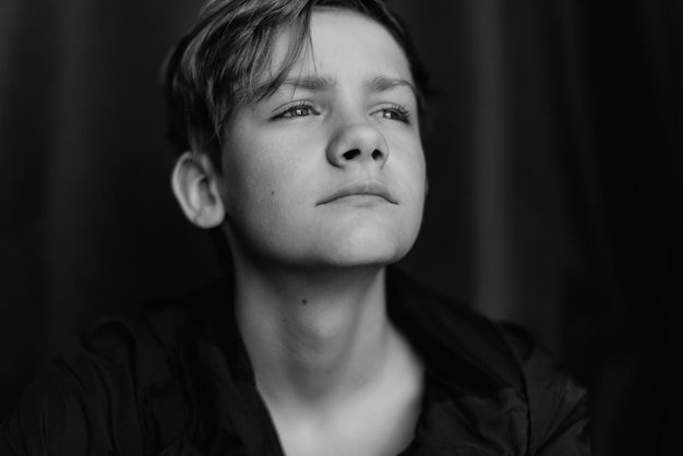 Retrato en blanco y negro de un adolescente sobre fondo oscuro Toma de primer plano de un joven adolescente Fotografía en blanco y negro Enfoque selectivo