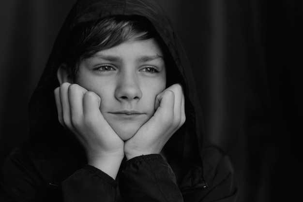 Retrato en blanco y negro de un adolescente sobre fondo oscuro Toma de primer plano de un joven adolescente Fotografía en blanco y negro Enfoque selectivo