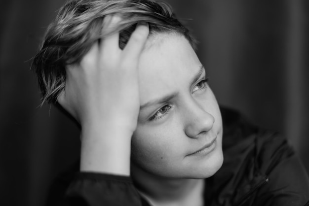 Retrato en blanco y negro de un adolescente sobre fondo oscuro Toma de primer plano de un joven adolescente Fotografía en blanco y negro Enfoque selectivo