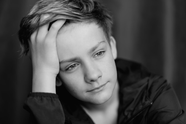 Retrato en blanco y negro de un adolescente sobre fondo oscuro Toma de primer plano de un joven adolescente Fotografía en blanco y negro Enfoque selectivo