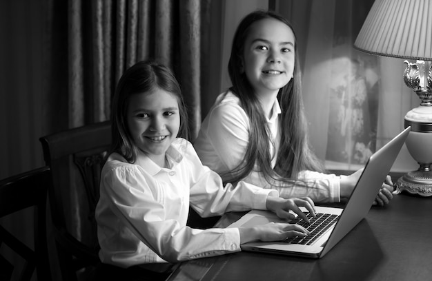 Retrato en blanco y negro de dos hermanitas usando laptop