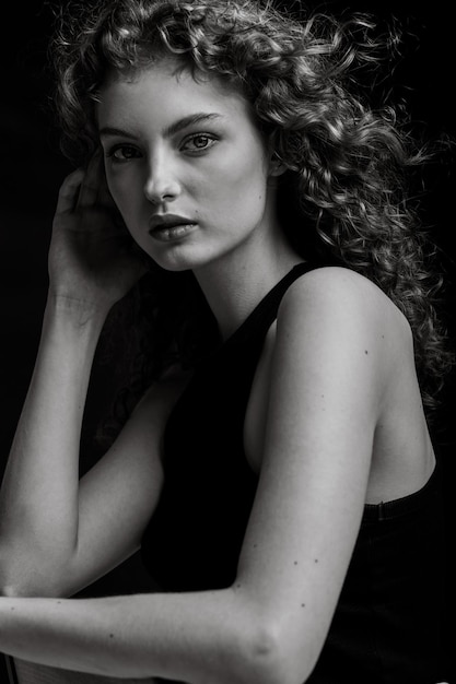 Retrato en blanco y negro de estudio de una joven modelo eslava de pelo rizado.