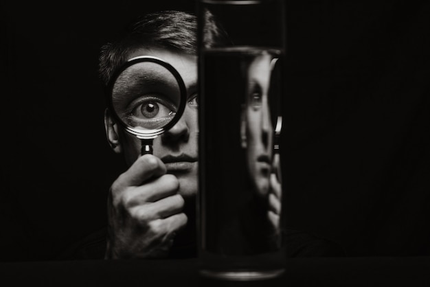Retrato en blanco y negro del hombre mirando a través de una lupa