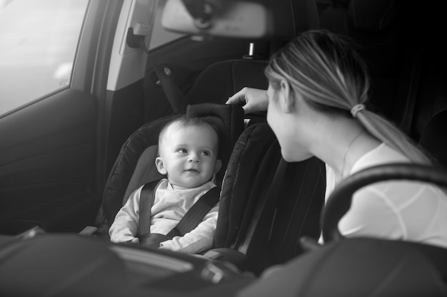 Retrato en blanco y negro de la madre mirando al bebé sentado en el asiento delantero del coche