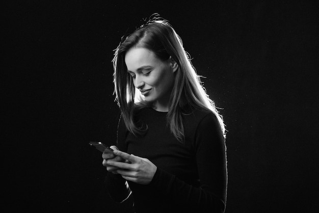 Retrato en blanco y negro de mujer joven mirando el teléfono y sonriendo