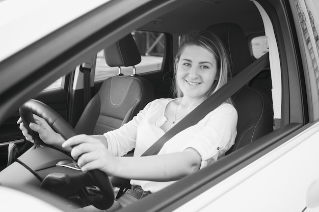 Retrato en blanco y negro de mujer sonriente conduciendo coche