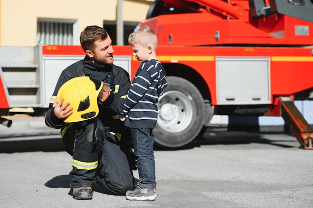 Retrato de un bombero de pie delante de un camión de bomberos