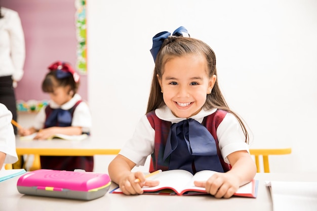 Retrato de una bonita niña de preescolar hispana en uniforme le encanta aprender y disfruta de su día en la escuela