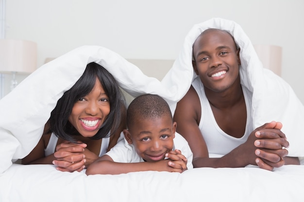 Retrato bonita pareja con su hijo en la cama junto