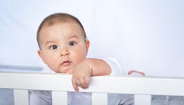 Retrato bonito de um bebê em um berço closeup uma criança em roupas brancas na cueca branca ternura e cuidados com os problemas das crianças