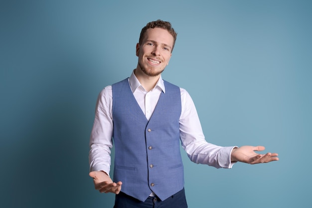 Retrato bonito homem animado em roupas de negócios sorrindo e mostrando a mão