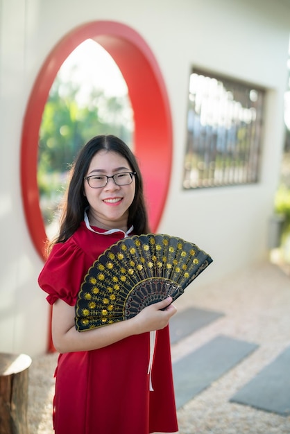 Retrato bonito sorri jovem asiática vestindo decoração chinesa tradicional vermelha e segurando um Fanning chinês para o Festival do Ano Novo Chinês no café do restaurante chinês