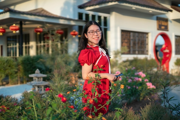 Retrato bonito sorri jovem asiática vestindo decoração chinesa tradicional vermelha e segurando um fanning chinês para o festival do ano novo chinês no café do restaurante chinês