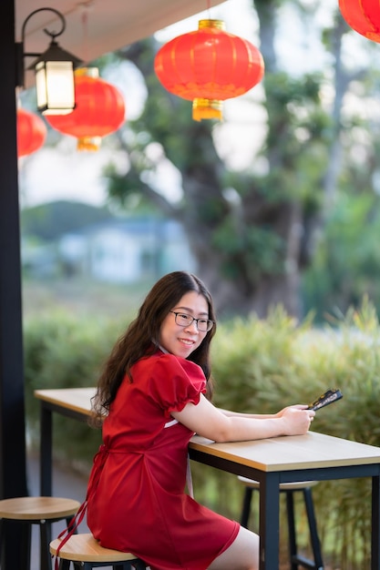 Retrato bonito sorri jovem asiática vestindo decoração chinesa tradicional vermelha e segurando um Fanning chinês para o Festival do Ano Novo Chinês no café do restaurante chinês
