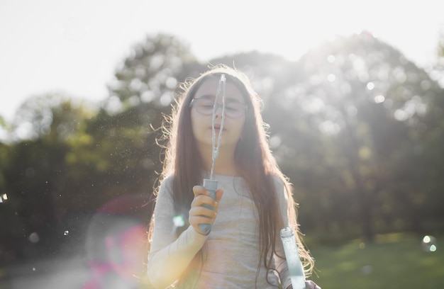 Foto retrato borroso de una hermosa chica caucásica que sopla pompas de jabón en un prado en un parque