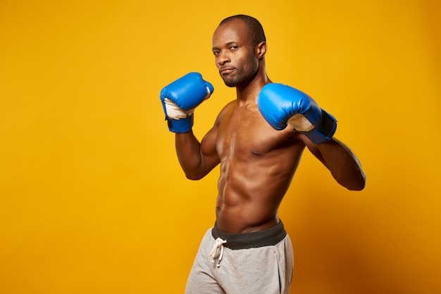 Retrato del boxeador atlético afroamericano en guantes azules.