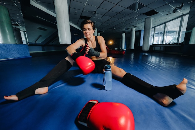 Retrato de una boxeadora en guantes rojos en el gimnasio después del entrenamiento