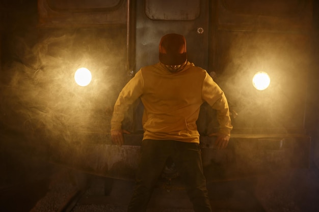 Retrato de breakdancer hipster b-boy preparándose para una actuación de pie en el humo en el tren del metro.