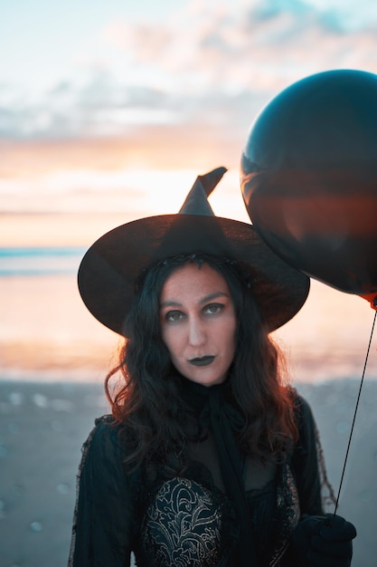 Retrato de una bruja latina con globos negros al atardecer al aire libre