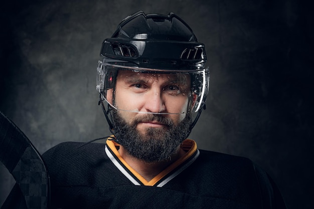 Retrato de un brutal hombre barbudo con uniforme y casco de jugador de hockey.