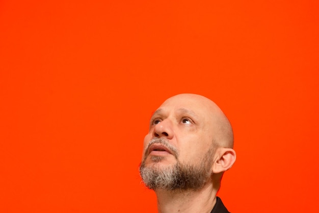 Foto retrato de la cabeza de un hombre calvo y barbudo aislado sobre fondo naranja