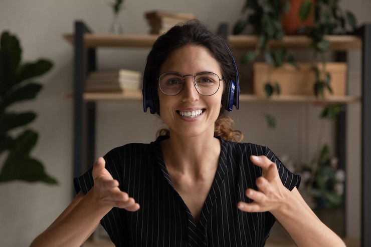 Foto retrato en la cabeza de una mujer sonriente con auriculares hablando en la cámara liderando una reunión o lección en internet maestra entrenadora filmando webinar amigable mujer de negocios consultora cliente llamada de video en línea