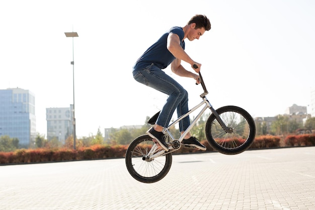 Retrato de la calle de un ciclista de bmx en un salto en la calle en el fondo del paisaje de la ciudad