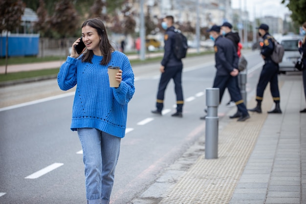 Retrato de la calle de una mujer joven hablando por teléfono en la ciudad cerca de la carretera