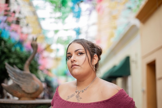 Retrato callejero de mujer joven mirando a la cámara con banderas multicolores en el fondo.