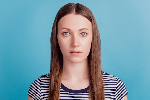 Retrato de cámara de mirada de chica encantadora centrada en calma sobre fondo azul.