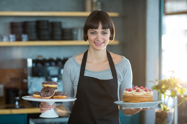 Retrato de camarera con donas y pastel en café