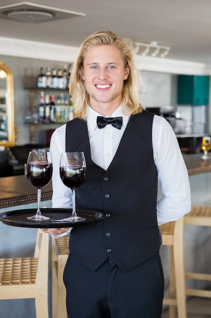 Retrato de camarero con bandeja con copas de vino tinto