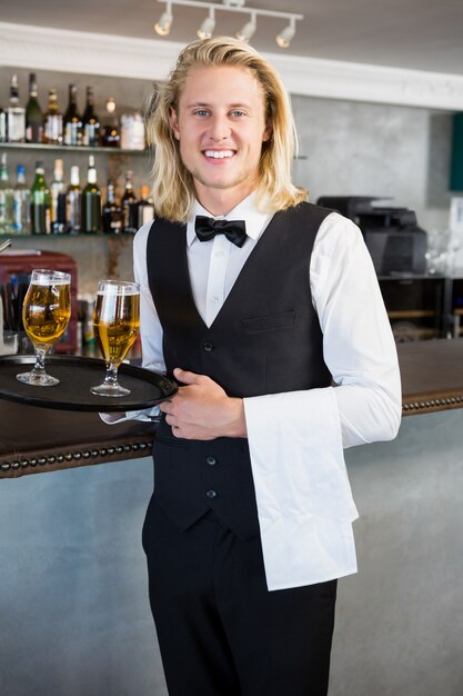 Retrato de camarero con bandeja con vasos de cerveza