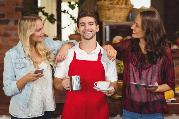 Retrato de un camarero sonriente y clientes en la cafetería