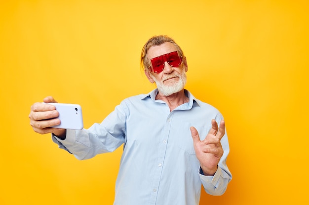 Retrato de camisas azules de hombre senior feliz con gafas toma un selfie inalterado
