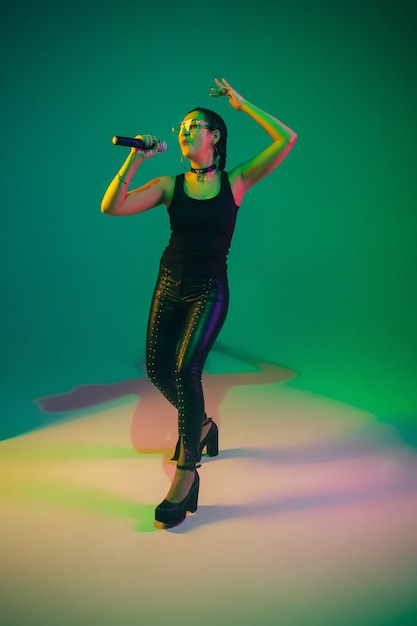 Retrato de cantante femenina caucásica aislado en la pared verde del estudio