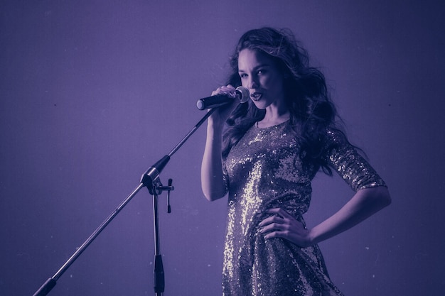 Retrato de cantante femenina caucásica aislado sobre fondo azul de estudio en luz de neón