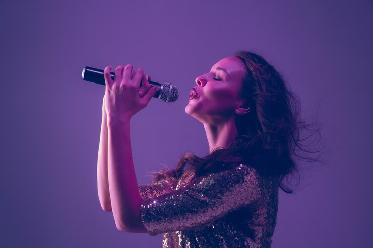 Foto retrato de cantante femenina caucásica aislado sobre fondo de estudio púrpura en luz de neón