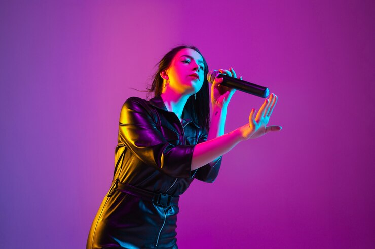 Foto retrato de cantante femenina caucásica aislado sobre fondo de estudio púrpura en luz de neón