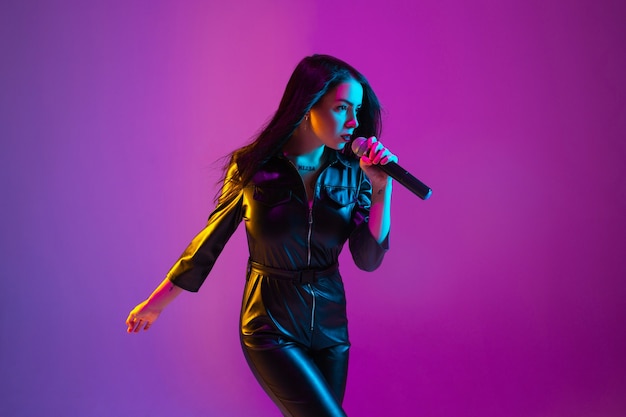 Foto retrato de cantante femenina caucásica aislado sobre fondo de estudio púrpura en luz de neón