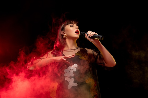 Retrato de cantante femenina caucásica aislado sobre fondo oscuro de estudio en luz de neón