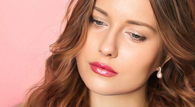 Retrato de cara de belleza mujer hermosa con peinado largo y ondulado y maquillaje elegante sobre fondo rosa maquillaje nupcial moda y modelo de glamour busca cosméticos para el cuidado de la piel y cuidado del cabello