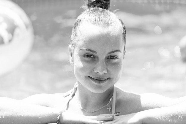 Retrato de cara de niño mojado feliz sonriendo en la piscina al aire libre en el día soleado de verano chica