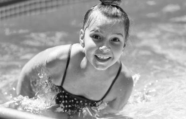 Retrato de cara de niño mojado feliz sonriendo en la piscina en el día soleado de verano chica