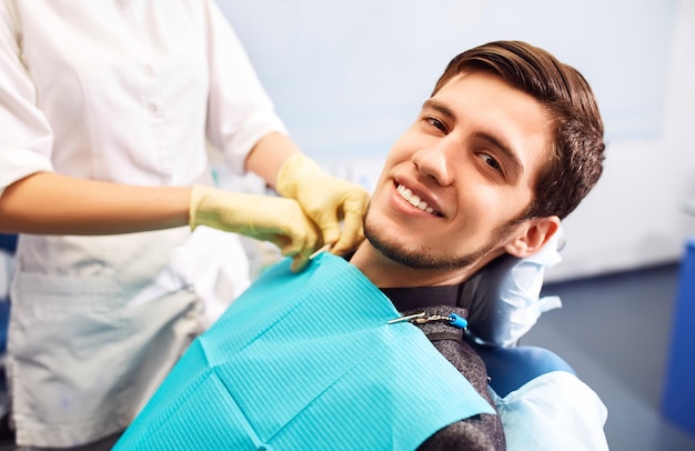 Retrato de cara de sonrisa masculina La inspección dental se le está dando a un hombre hermoso rodeado de dentista