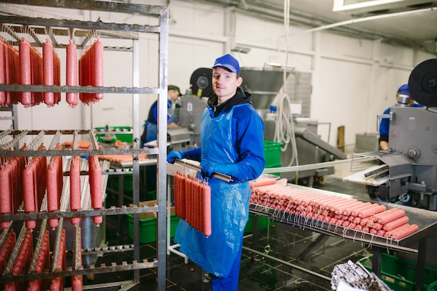 Retrato de carniceros procesando salchichas en la fábrica de carne