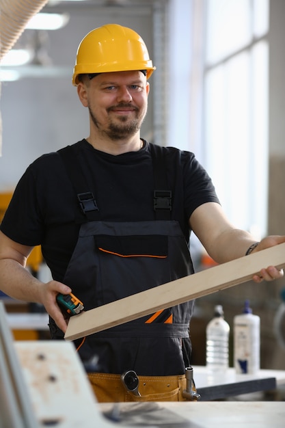 Retrato de un carpintero sonriente con tablones de madera