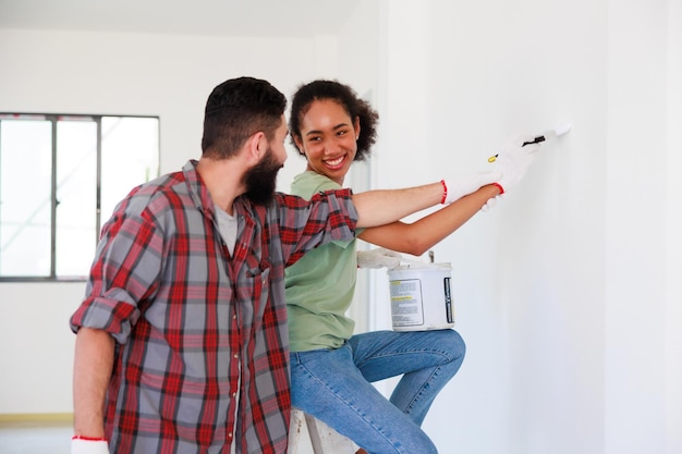 Retrato casal alegre jovem e mulher negra sorrindo durante a renovação no novo apartamento jovem família feliz renovando a casa e planejando o quarto