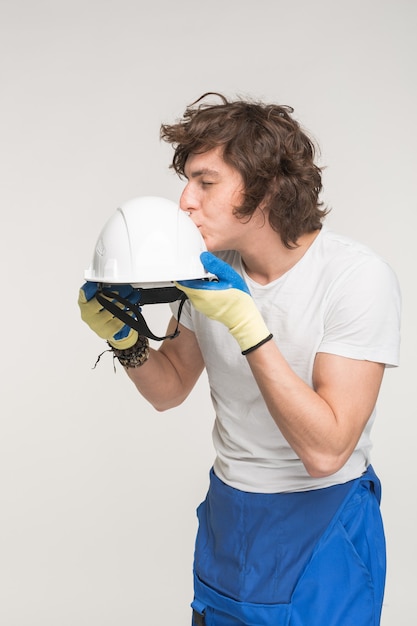 Retrato de casco de besos divertido constructor masculino caucásico sobre fondo blanco.