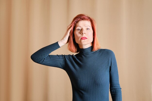 Retrato casual de mulher de meia idade tocando seu cabelo vermelho